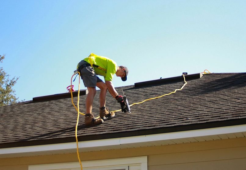 Roofer making a roof repair with a nail gun