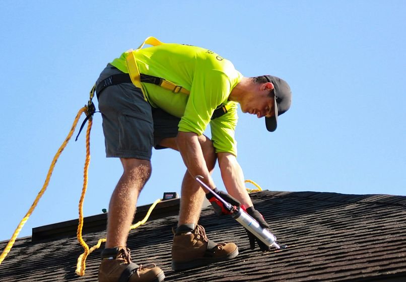 Roofer repairing an asphalt shingle roof